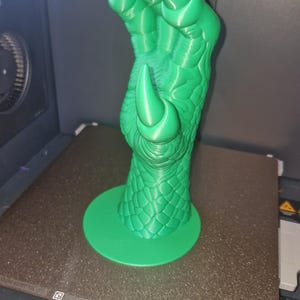Könnte beinhalten: Eine 3D-gedruckte, hellgrüne Drachenklauen-Skulptur. Die Klaue weist detaillierte Schuppen und scharfe Krallen auf und steht auf einem kreisförmigen Sockel. Die Skulptur hat eine leuchtend grüne Farbe und scheint aus Kunststoff zu bestehen.