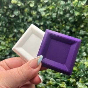 May include: A set of three ceramic mugs with a speckled, matte finish. The mugs are in shades of cream, light gray, and dark gray. Each mug has a simple, minimalist design and a rounded handle.