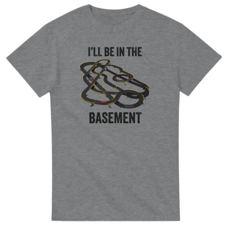 May include: A heather gray t-shirt with the text "I'LL BE IN THE BASEMENT". The shirt features a graphic of a black and yellow race track design.