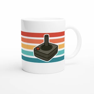 May include: White ceramic mug featuring a retro video game joystick design. The mug has a black joystick graphic with a red button, set against a backdrop of horizontal stripes in red, orange, yellow, teal, and blue.