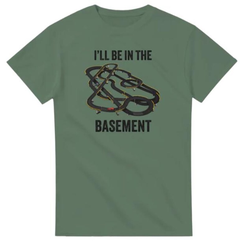 May include: Green t-shirt with the text "I'LL BE IN THE BASEMENT" above a graphic of a slot car race track. The track is black with yellow and red accents. The shirt is a solid green color.