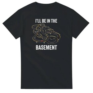 May include: Black t-shirt with the text "I'll Be In The Basement" above a graphic of a race track. The track design is in shades of gray and gold.