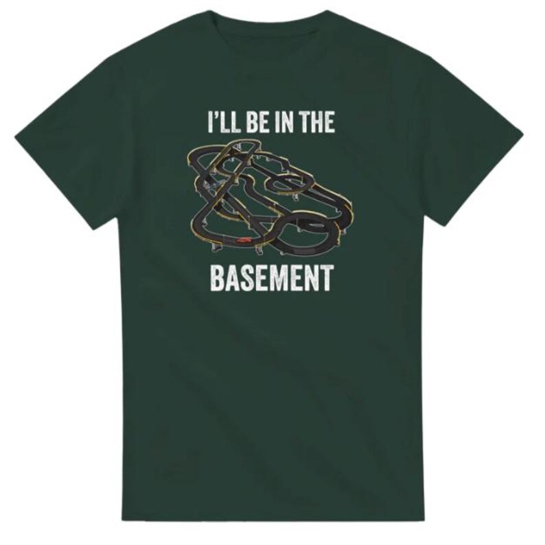 May include: Dark green t-shirt with the text "I'll be in the basement" in white. The shirt features a graphic of a race track in black and gold.