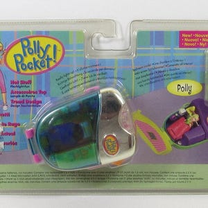 May include: Polly Pocket playset in original packaging. The set includes a compact, a Polly Pocket figure, and accessories. The packaging features the Polly Pocket logo, a cartoon illustration, and text in multiple languages.