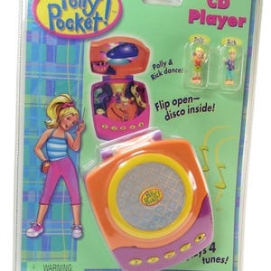 Peut inclure: Un jouet Polly Pocket CD Player dans son emballage d'origine. Le lecteur orange et violet a un haut-parleur et des boutons. L'emballage présente un dessin animé de Polly et Rick, et le texte "Flip open-disco inside!" et "Plays 4 tunes!"