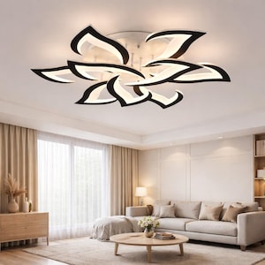 May include: A modern ceiling light fixture with a floral design. The light features black and white petal-shaped elements, creating a unique and stylish look. The fixture is mounted on a white ceiling, illuminating a living room with neutral tones.