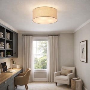 May include: A beige drum-shaped ceiling light fixture illuminates a home office. The light has a fabric shade and is centered in the room. The office features a desk, chair, and a window with white curtains.