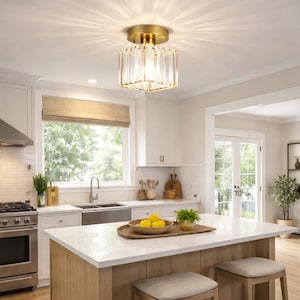 May include: A gold-toned, square flush mount ceiling light with clear crystal accents. The light fixture is installed in a kitchen with white cabinets, a stainless steel sink, and a wooden island with stools. The room has a bright, airy feel.