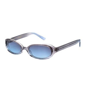Puede incluir: Gafas de sol ovaladas con montura gris translúcida y lentes degradadas azules. Las patillas son de un gris más oscuro y las puntas son de color azul claro. Estas gafas ofrecen un aspecto elegante y moderno.