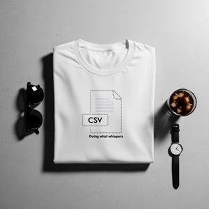 May include: White t-shirt featuring a black CSV file graphic and the phrase "Doing what whispers." The image includes black sunglasses, a watch, and a glass of iced coffee. The items are arranged on a grey surface. A casual, everyday wear item.