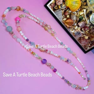 May include: Multi-colored beaded necklaces with various sizes and shapes of beads. The necklaces include pink, purple, blue, and orange beads. The text "Save A Turtle Beach Beads" is displayed on the image.