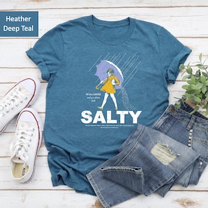 Sassy meets soft! ✨ Our Salty Girl Shirt blends vintage vibes with modern comfort. Made for sunny days and salty hair, this trendy graphic tee is your new favorite summer essential. Perfect casual top or thoughtful gift for her!