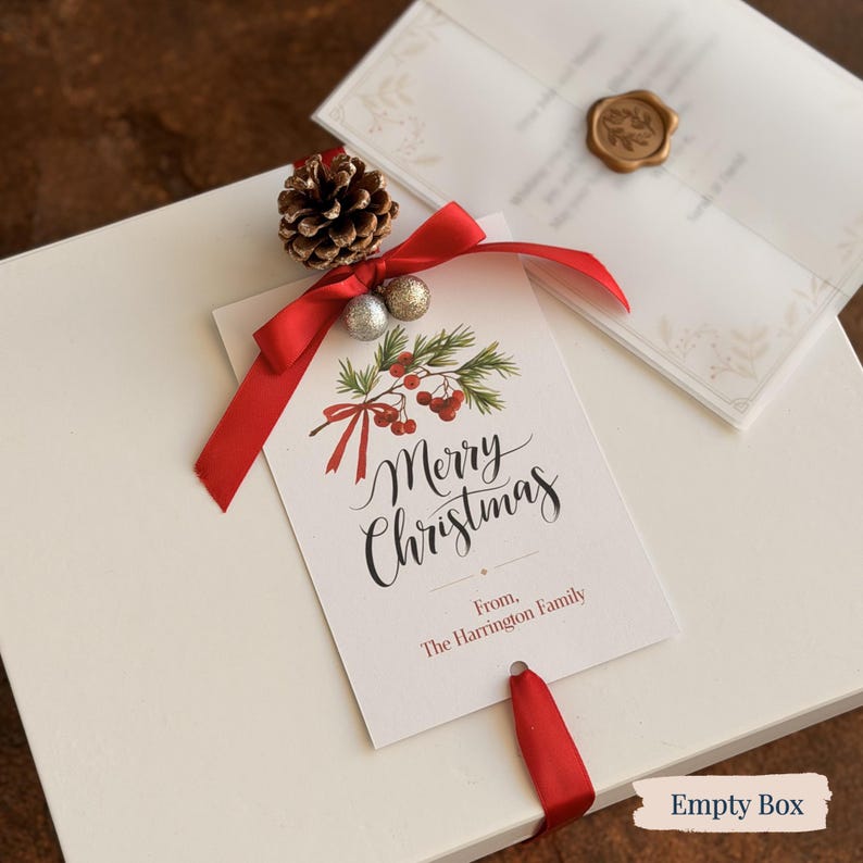 May include: A white gift box tied with a red ribbon and a Christmas tag. The tag reads "Merry Christmas" with a festive design of berries and foliage. A pinecone and silver and gold baubles decorate the box.