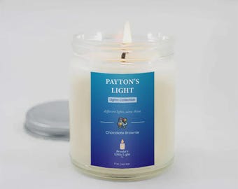 May include: A lit glass jar candle with a blue and white label that reads "PAYTON'S LIGHT Lights Collection Chocolate Brownie." The candle is 255 grams.