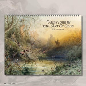 May include: A 2027 wall calendar titled Fairy Lore in the Art of Olde, featuring a horizontal spiral binding at the top. The cover displays a detailed landscape painting of a forest scene with figures near a river, rendered in muted earth tones.