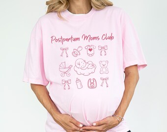 Może przedstawiać: Jasnoróżowa koszulka z napisem "Postpartum Moms Club" i ilustracjami związanymi z dziećmi. Projekt zawiera kokardy, smoczek, body, dziecko w chmurze, wózek, misia, butelkę i śliniaczek.