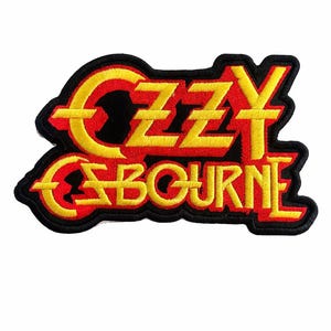 May include: Embroidered patch featuring the name "OZZY OSBOURNE" in yellow and red lettering. The patch has a black border and is designed with a stylized font. The patch is likely for a jacket or bag.
