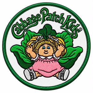 May include: A circular embroidered patch featuring the Cabbage Patch Kids logo in green text above a cartoon character with blonde pigtails, blue eyes, and a pink dress, sitting in front of large green cabbage leaves on a white background.