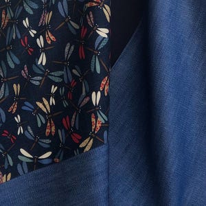 Puede incluir: Primer plano de una tela con un estampado de lib&eacute;lulas en azul marino, blanco, rojo y beige. La tela est&aacute; junto a una tela azul liso. La tela de lib&eacute;lulas se utiliza probablemente para ropa o decoraci&oacute;n del hogar.