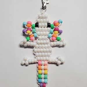 May include: A beaded axolotl keychain in white, with colorful accents. The axolotl features rainbow gills and a tail, with black eyes. The keychain has a silver clasp. The axolotl is made of small, round beads.