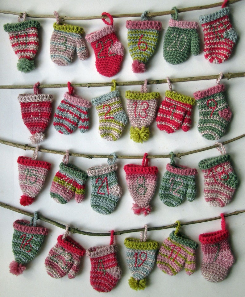 May include: A string of 24 crocheted mitten ornaments, each with a different number from 1 to 24. The mittens are in various colors, including red, pink, green, and blue. The mittens are hung on a branch with twine.