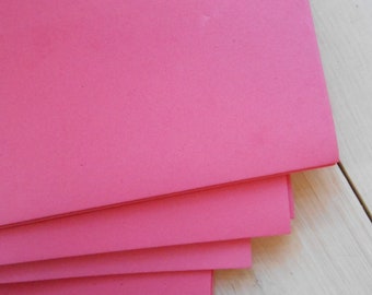 May include: Stack of four pink foam sheets. The sheets are smooth and have a slightly textured surface.