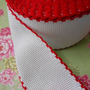 May include: White and red trim ribbon with a scalloped edge. The ribbon is made of a woven fabric and is perfect for adding a touch of elegance to any project.