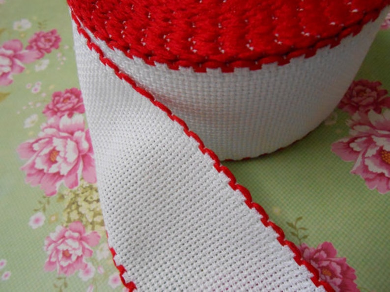 May include: White and red trim ribbon with a scalloped edge. The ribbon is made of a woven fabric and is perfect for adding a touch of elegance to any project.