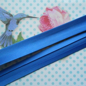 May include: Two pieces of blue elastic ribbon, one wider than the other, are laid out on a white background with blue polka dots.