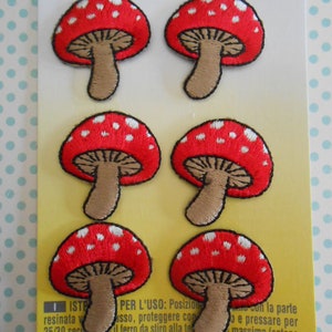 May include: Six red and white mushroom iron-on patches. The mushrooms have white polka dots and brown stems.