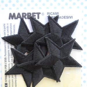 Op de afbeelding: Een pak met zes zwarte, strijkbare, geborduurde ster-patches. De patches zijn ongeveer 5 cm in diameter. De verpakking bevat instructies voor gebruik in het Italiaans.