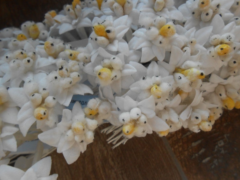 May include: A bunch of white fabric flowers with yellow centres. The flowers are arranged in a cluster and have a delicate, feminine appearance.