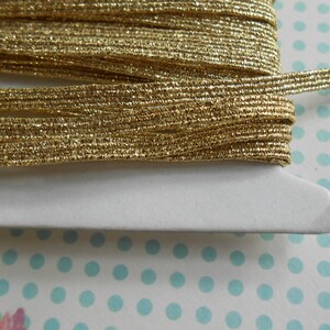 May include: A spool of gold metallic elastic trim. The trim is thin and has a subtle shimmer.