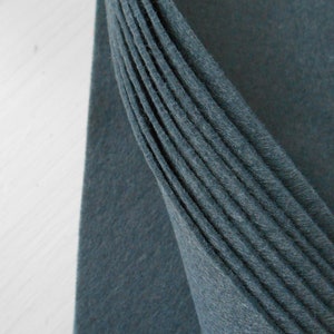May include: A stack of folded teal blue felt fabric. The fabric is soft and has a slightly textured surface.