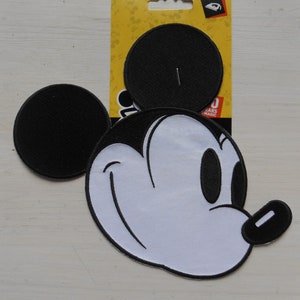 May include: A black and white Mickey Mouse iron-on patch with a smiling face and two black ears. The patch is on a yellow backing card with the words "50 Years of Magic".