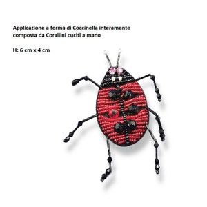 May include: A handmade ladybug brooch, 2.4 inches by 1.6 inches, made of red and black beads. The ladybug has black legs and antennae, with pink and black accents. The text on the image says "Application in the form of a ladybug entirely composed of hand-sewn Corallini".
