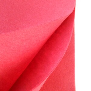 Peut inclure: Un gros plan sur un tissu en feutre rouge vif plié en deux. Le tissu est doux et texturé, avec un léger brillant.