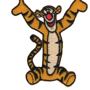 May include: A yellow and black embroidered iron-on patch of Tigger from Winnie the Pooh. Tigger is standing with his arms raised and a big smile on his face.