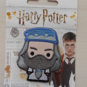 May include: A grey and blue embroidered iron-on patch featuring a cartoon illustration of a wizard with a long grey beard and a blue hat. The patch is on a white background with a newspaper print pattern. The text "Harry Potter" is printed in gold at the top of the image.