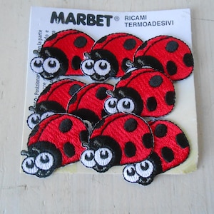 Op de afbeelding: Een vel geborduurde lieveheersbeestjespatches. Elk lieveheersbeestje is rood met zwarte stippen en een zwarte kop met witte ogen. De patches zitten op een witte achtergrond met de merknaam "MARBET" bovenaan.