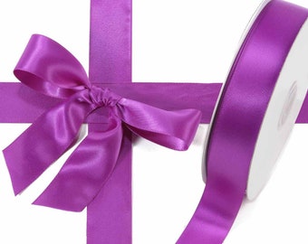 May include: A roll of purple satin ribbon with a matching bow. The ribbon is a vibrant shade of purple and appears to be unwound, with a bow tied in the center. The ribbon is on a white background.