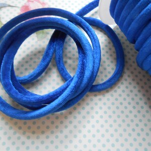 May include: A spool of bright blue velvet cord, wound tightly and ready to be used for crafting projects.