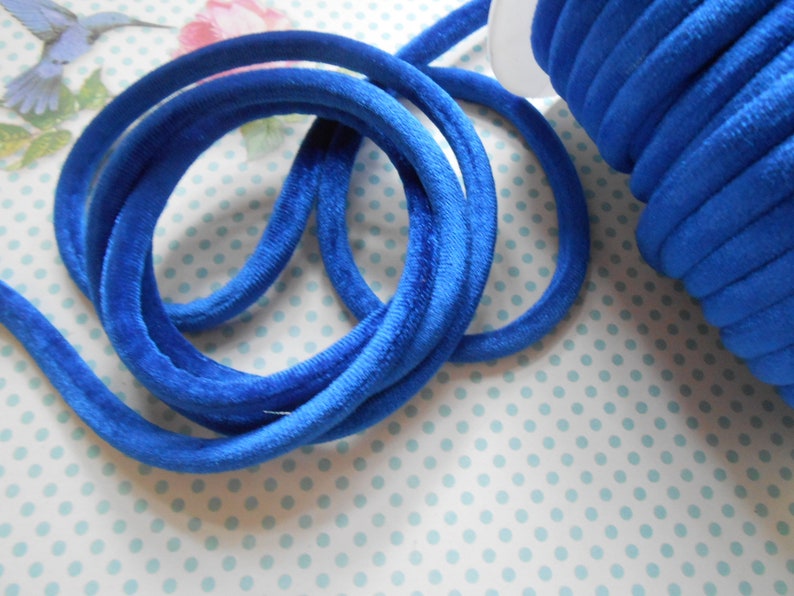 May include: A spool of bright blue velvet cord, wound tightly and ready to be used for crafting projects.