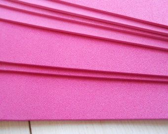 May include: A stack of bright pink foam sheets. The sheets are rectangular and have a slightly textured surface. The edges are clean and straight, and the sheets are neatly stacked. The color is a vibrant, solid pink.