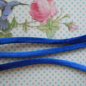 May include: Three strands of royal blue velvet cord, each about 1/2 inch wide, are laid out on a white background with blue polka dots.