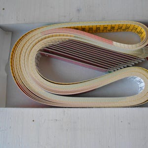 May include: A collection of measuring tapes and cards in a white box with a red accent. The tapes are yellow with black markings, and the cards are red and white. The tapes are curled in a loop.