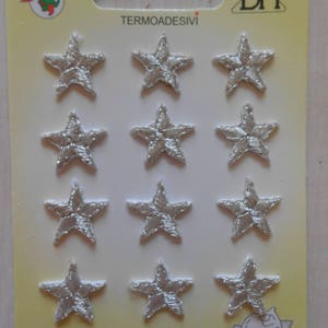 Könnte beinhalten: Eine Folie mit 12 silbernen, aufbügelbaren Sternen. Die Folie ist gelb mit dem Text "TERMOADESIVI" und "BM" in einem weißen Kreis.