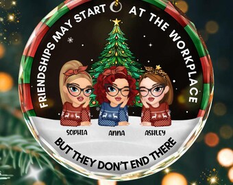 May include: A round Christmas ornament with a festive design. It features three cartoon women in sweaters, with the names Sophia, Anna, and Ashley. The ornament has text that reads "Friendships May Start At The Workplace But They Don't End There."