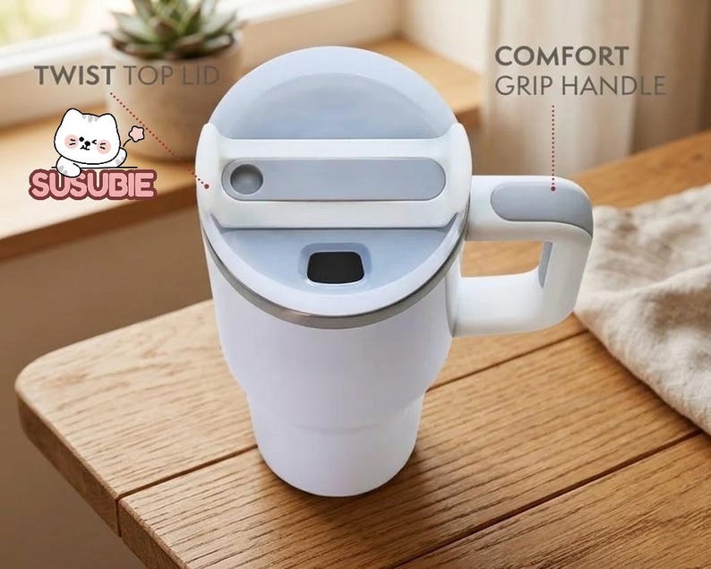 A white and gray insulated travel mug with a twist-top lid and a comfortable grip handle, placed on a wooden table.