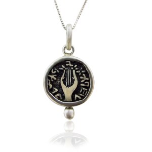 May include: Silver pendant necklace featuring a replica of an ancient coin with a lyre and Hebrew text. The pendant is attached to a silver chain.
